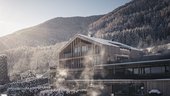 Eine regenerierende Auszeit vor Weihnachten Modernes Holzhaus mit Schnee und Nebel vor bewaldetem Berg