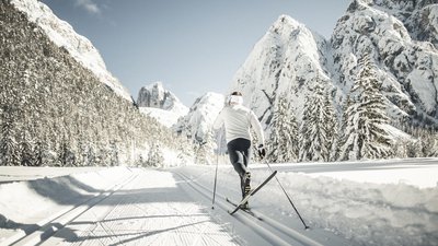 Sciatore di fondo su pista innevata in montagna soleggiata