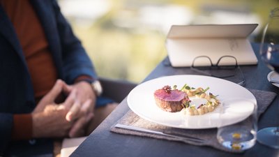 Bistecca finemente impiattata con verdure e salsa su piatto bianco