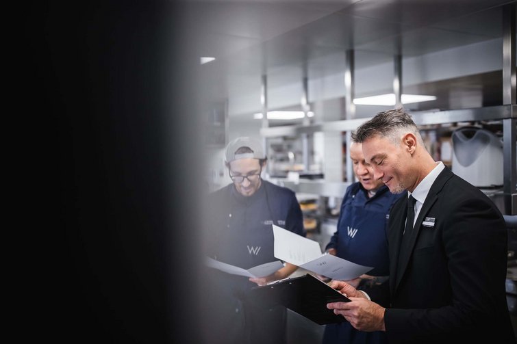 Direttore d'albergo che discute i menu con il personale di cucina in cucina