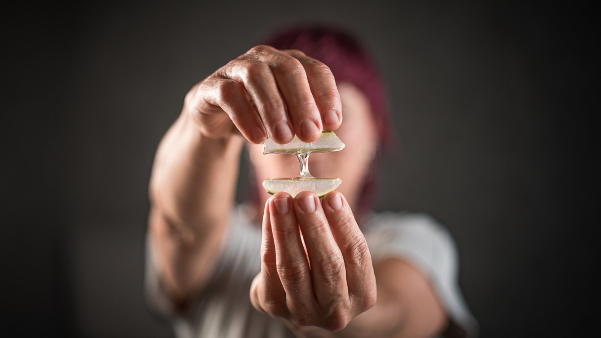 Person presst Aloe Vera Blätter, Gel tropft zwischen den Händen