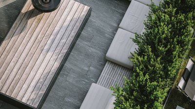 Area esterna moderna con divani grigi, tavolo in legno e piante