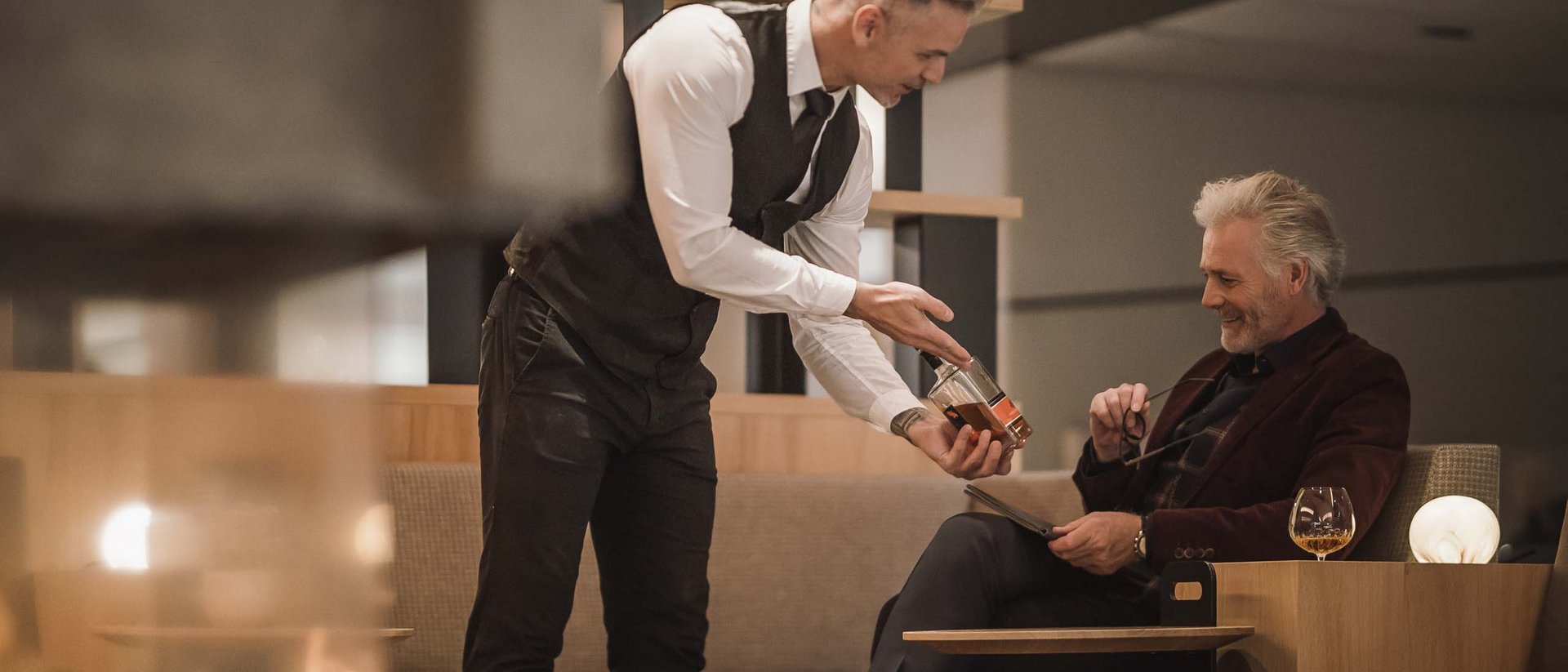 Cameriere serve un drink a un uomo anziano in un ristorante