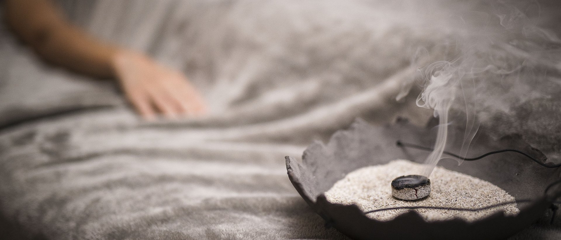 Räucherkohle mit aufsteigendem Rauch auf einem weichen grauen Tuch