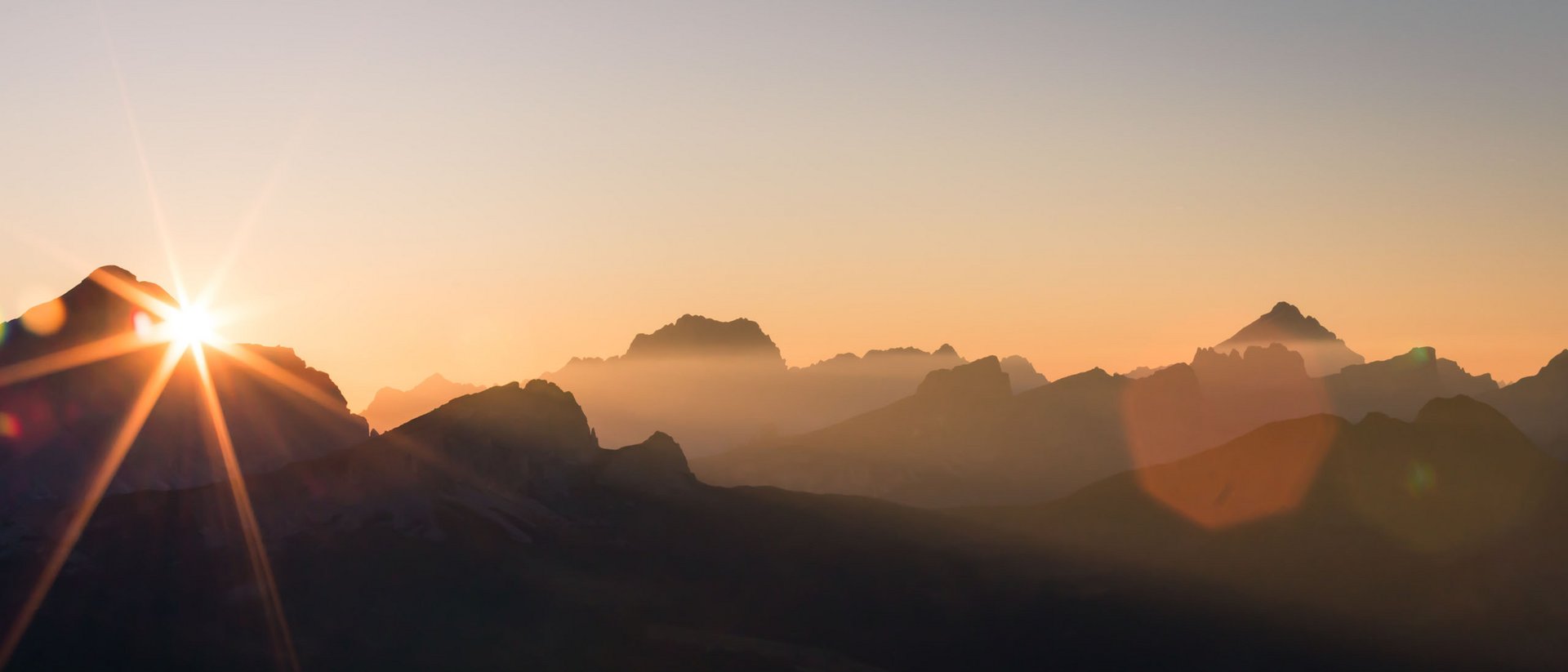 Alba dietro le montagne con nebbia e cielo sereno