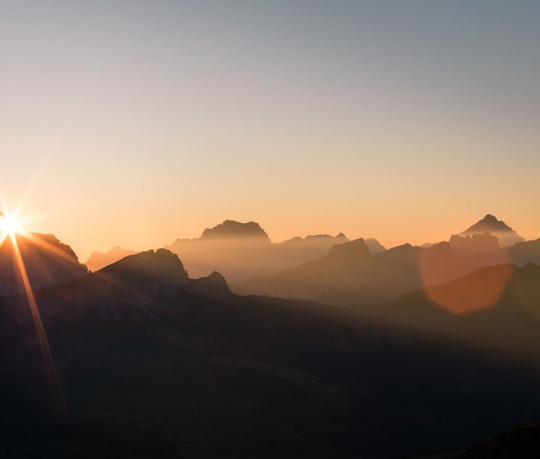 Alba dietro le montagne con nebbia e cielo sereno