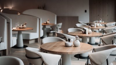 Photos from your hotel in Pfalzen in Val Pusteria/Pustertal Elegant modern restaurant with wooden tables and beige upholstered chairs