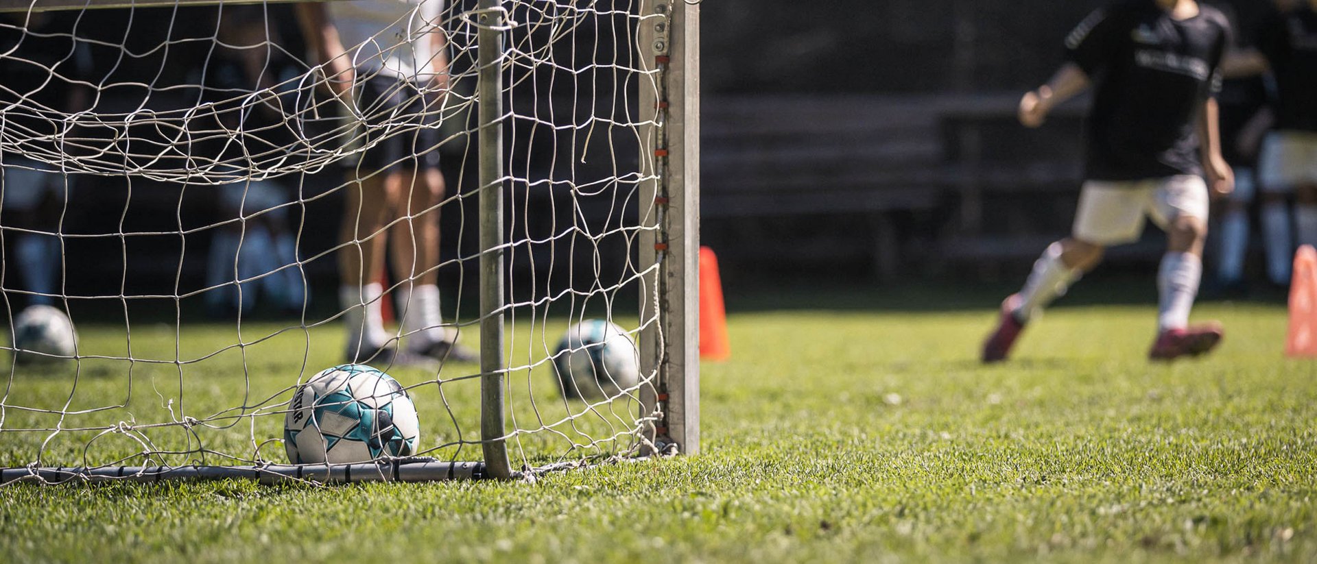 Soccer game with small goal and ball in net on green grass