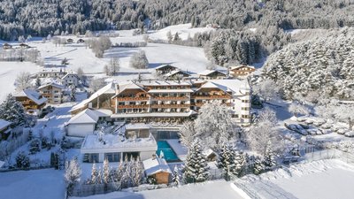The best photos from our hotel in South Tyrol that kids love Snow-covered mountain hotel complex with pool and forest in background