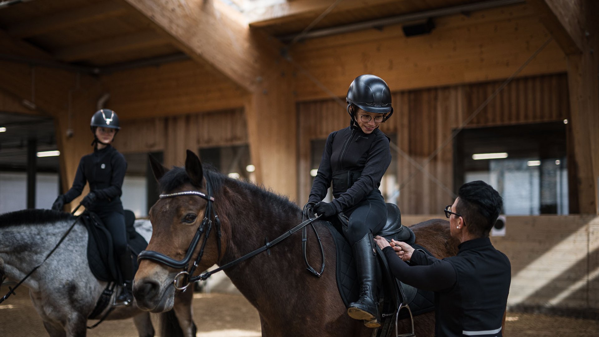 Kind lernt Reiten in Reithalle mit Hilfe eines Ausbilders