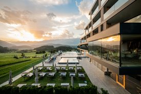 Eine regenerierende Auszeit vor Weihnachten Moderner Hotelpool mit Sonnenliegen und Bergblick bei Sonnenuntergang