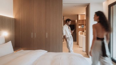 Room with large bed, wooden wardrobe, and man using a tablet