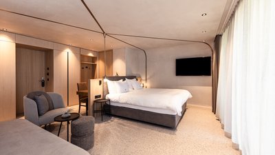 Camera d'albergo moderna con letto matrimoniale, zona salotto e TV