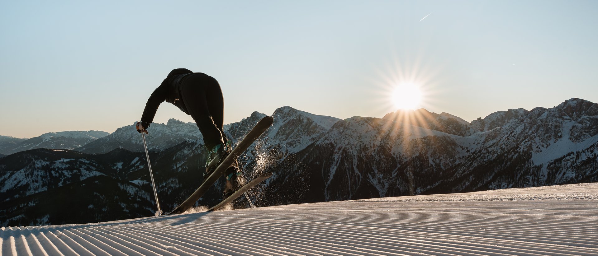 Hotel sulle piste del Plan de Corones: divertimento senza fine Sciatore salta su pista fresca al tramonto tra le montagne