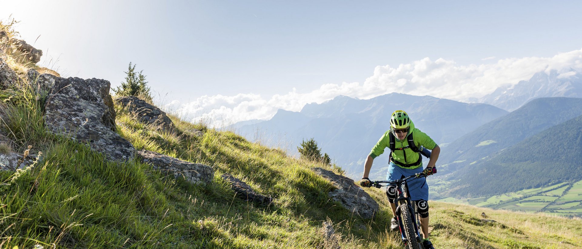 Mountain biker riding on mountain trail with mountain landscape in background