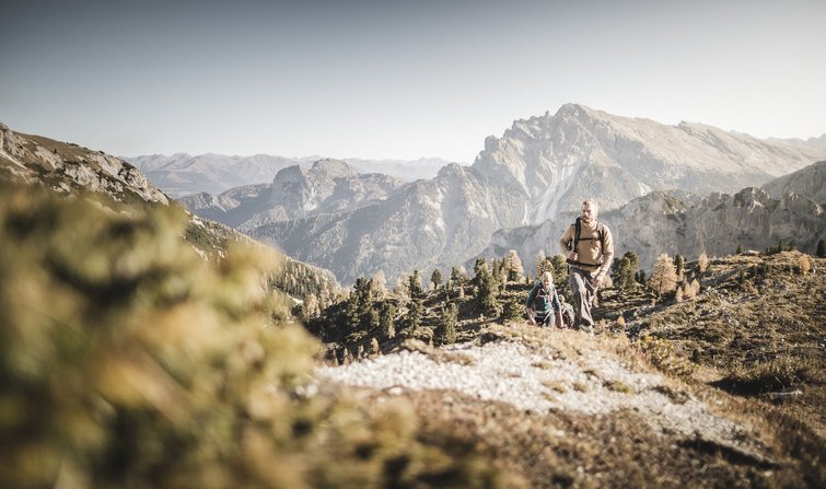 Hikers in mountains with mountain range in background under clear sky
