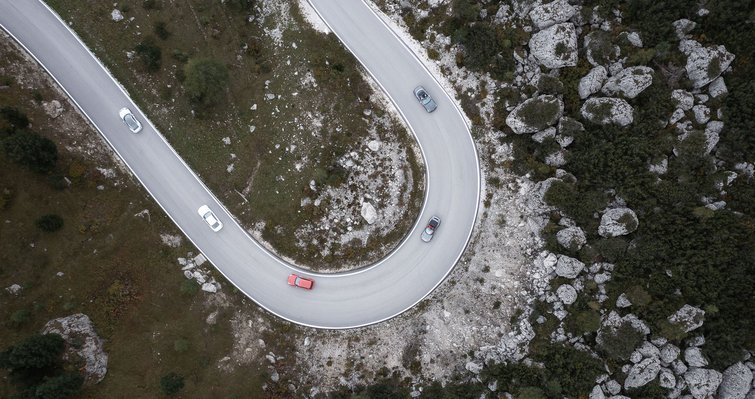 Aerial view of a winding mountain road with cars and rocky terrain