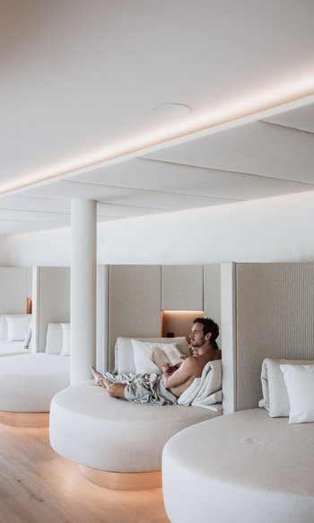 Mann entspannt auf rundem Sofa in modernem, hellen Ruhebereich