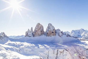 Snow-covered Dolomite peaks under bright sun and clear blue sky
