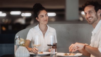 Two people eating and drinking wine at a restaurant