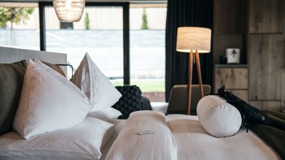 L’esclusività in foto: il nostro chalet in Alto Adige di lusso Letto accogliente con cuscini bianchi e illuminazione moderna in stanza