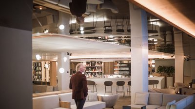 Uomo in lounge bar con divani e sgabelli