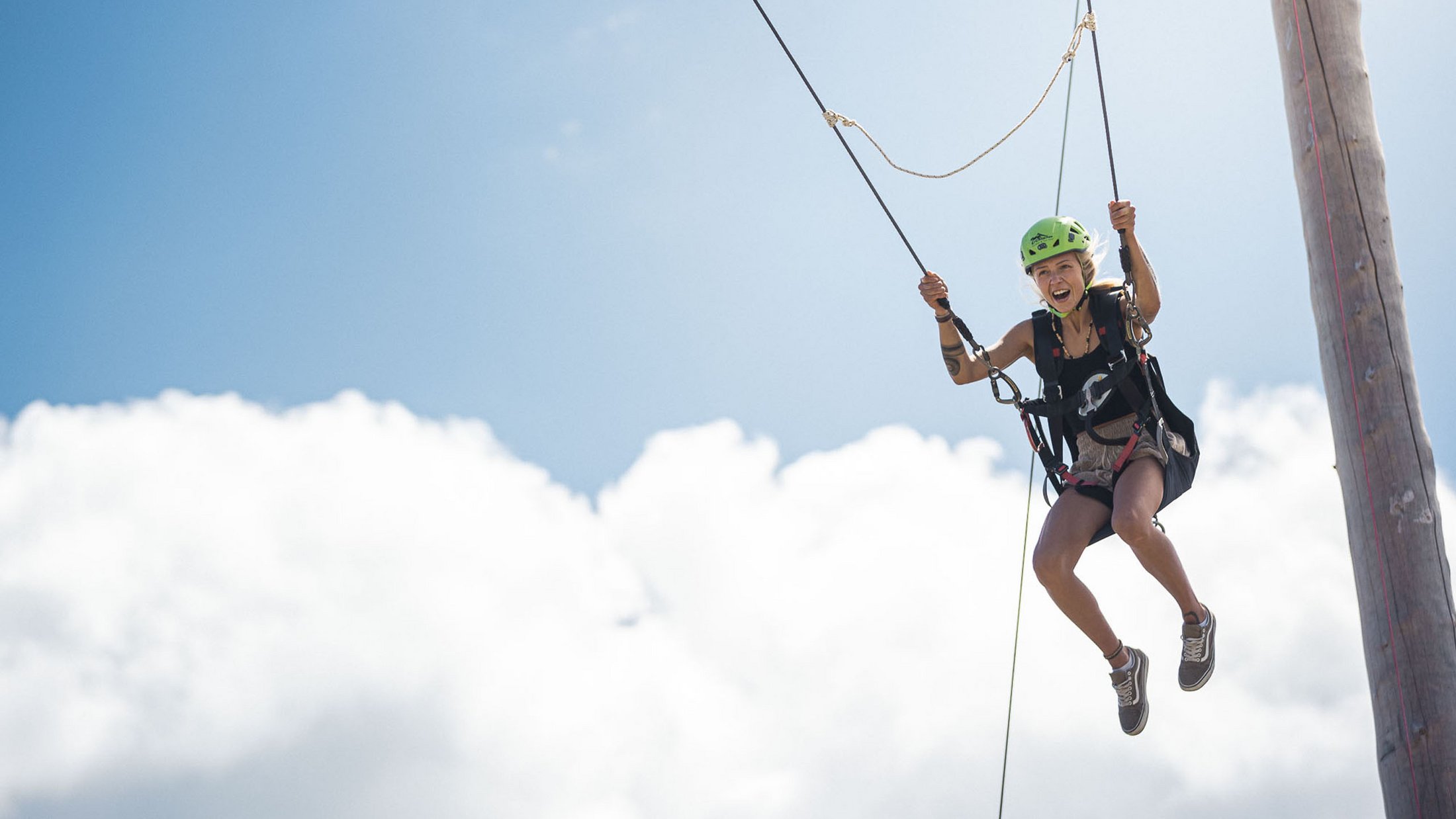 Donna con casco su teleferica contro cielo azzurro con nuvole