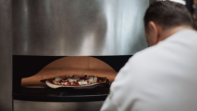 Photos from your hotel in Pfalzen in Val Pusteria/Pustertal Man baking a pizza in a professional oven