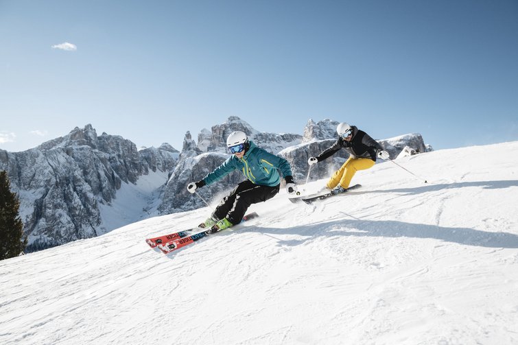 Hotel sulle piste del Plan de Corones: divertimento senza fine Due sciatori con abbigliamento colorato sciano velocemente su una pista innevata in montagna