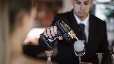 Uomo in abito crea fumo in una bolla sopra un calice da vino