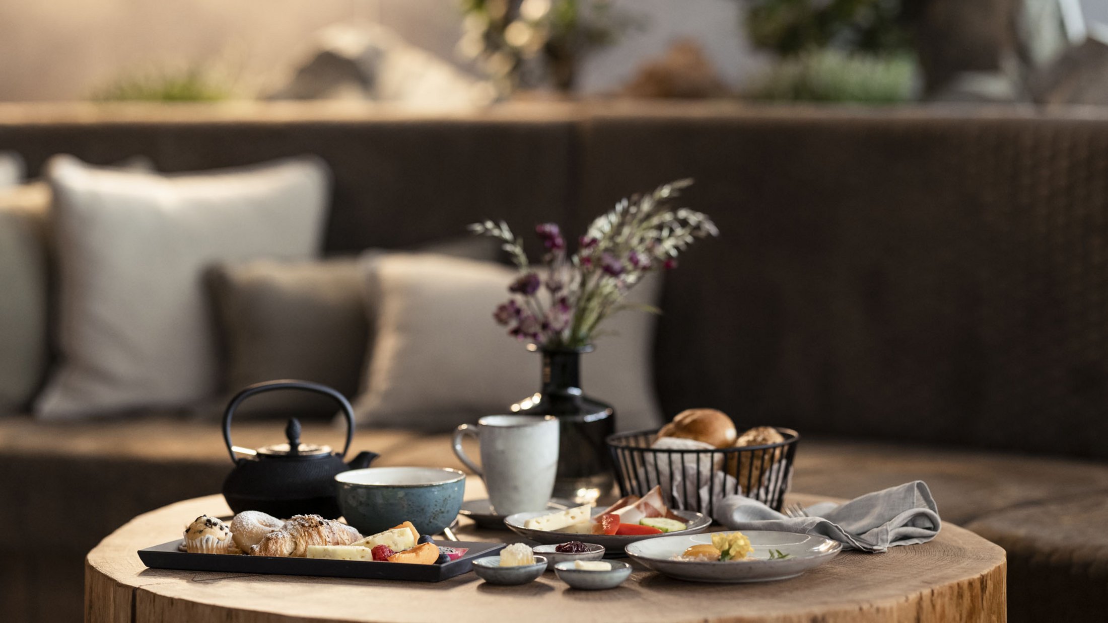 Gemütliche Frühstücksszene mit Gebäck, Käse, Teekanne und Dekoration