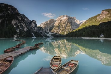 Boats on clear mountain lake with reflection of mountains and forest in background