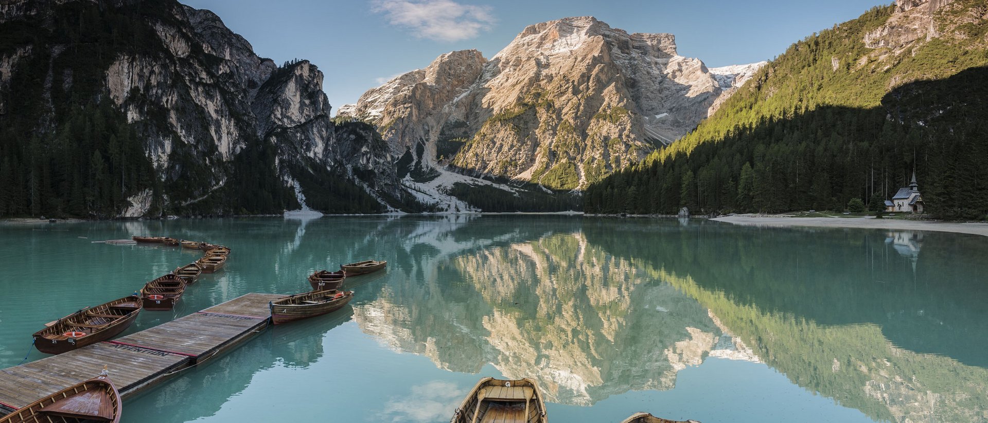 Bergseen und Badesee rund um die Winklerhotels Boote auf klarem Bergsee mit Spiegelung der Berge und Wald im Hintergrund