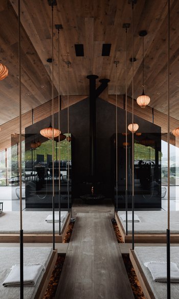 Spa moderno con letti sospesi, specchi e accenti caldi in legno