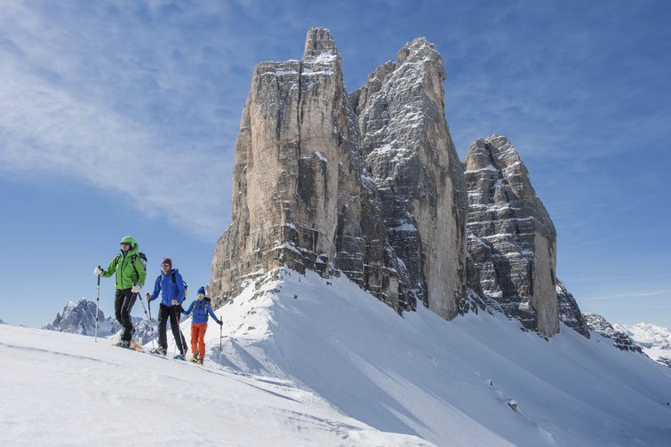 Three ski mountaineers in front of the snowy rock formations of the Three Peaks in the Alps