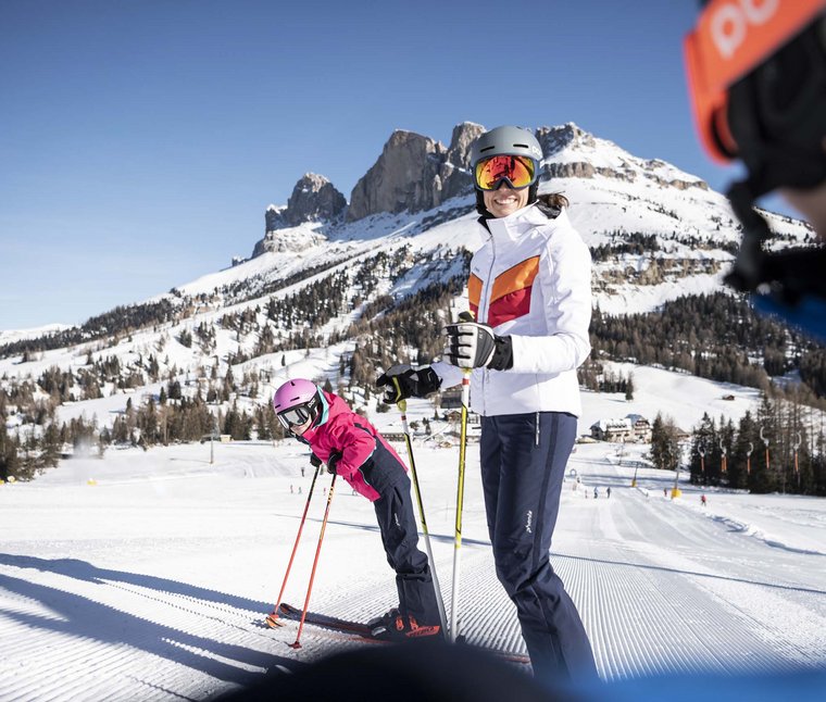 Donna e bambino sciando su pendio innevato con montagne sullo sfondo