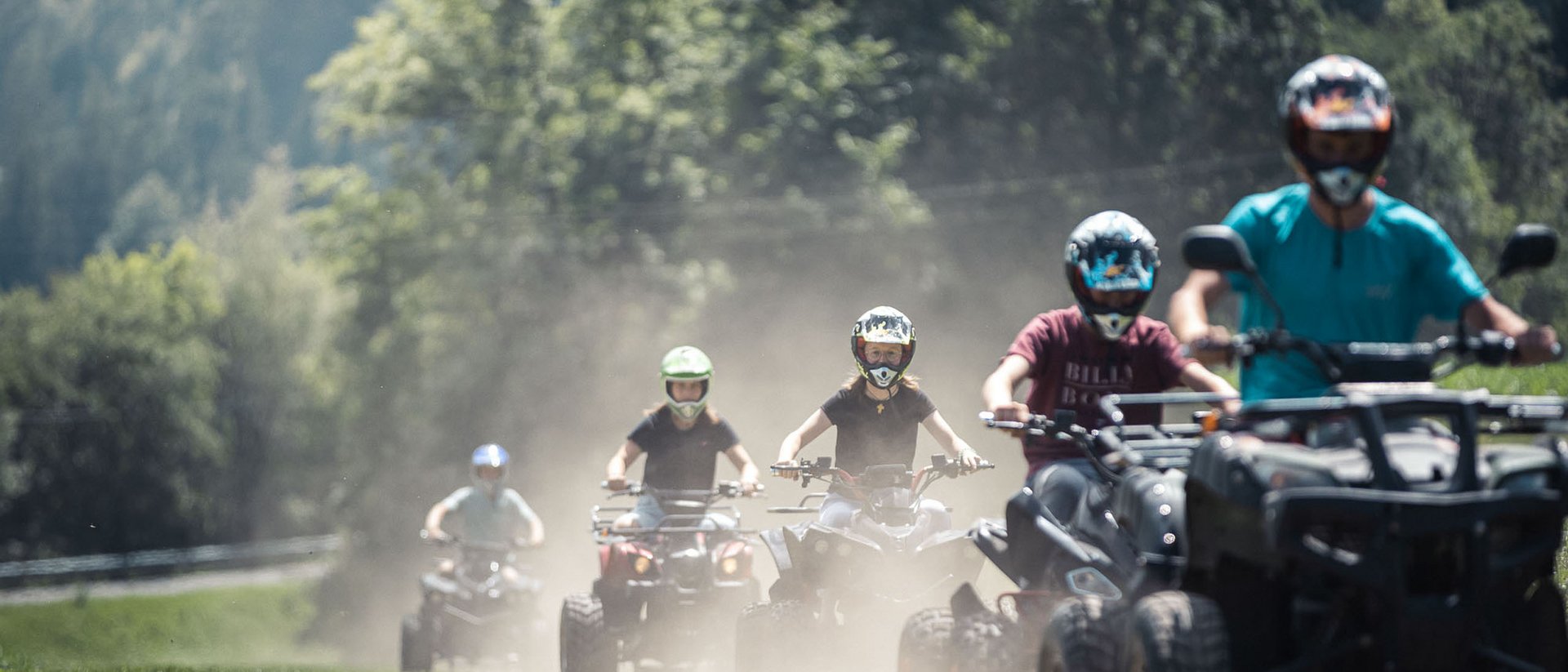 Gruppe von Menschen, die auf Geländefahrzeugen auf staubigem Weg fahren