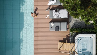 The best photos from our hotel in South Tyrol that kids love Woman sitting by pool next to loungers and hot tub on wooden deck