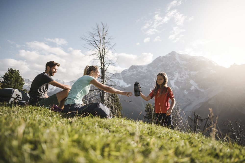 Sentiero delle fiabe a Tesido, attrazione per tutti Famiglia in montagna che si passa una borraccia d'acqua durante l'escursione