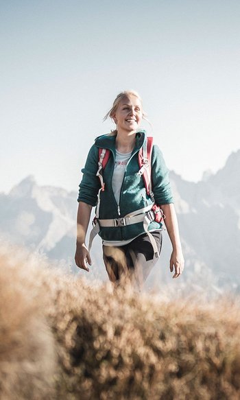 Tre escursionisti con zaini su sentiero di montagna con cielo limpido