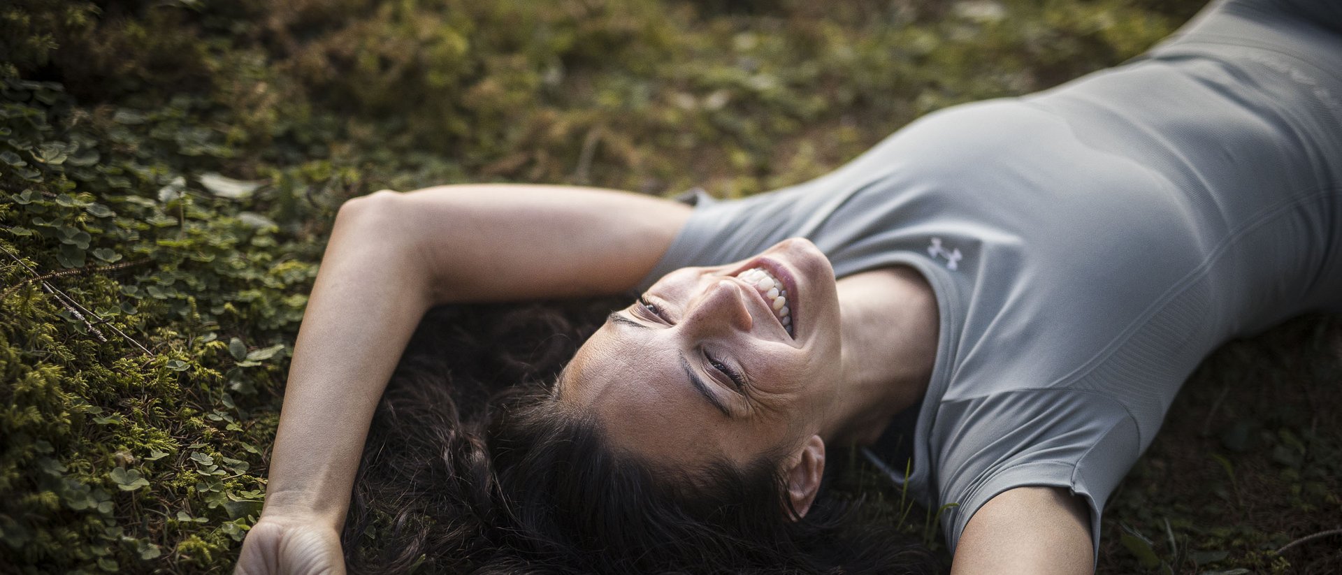 Woman smiling lying on mossy ground in nature