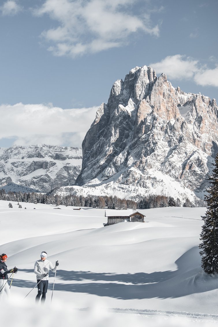 Due sciatori in paesaggio innevato con grande montagna e cielo sereno