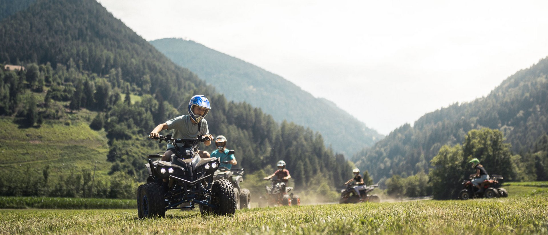 Kinder fahren Quad in bergiger Landschaft bei sonnigem Wetter