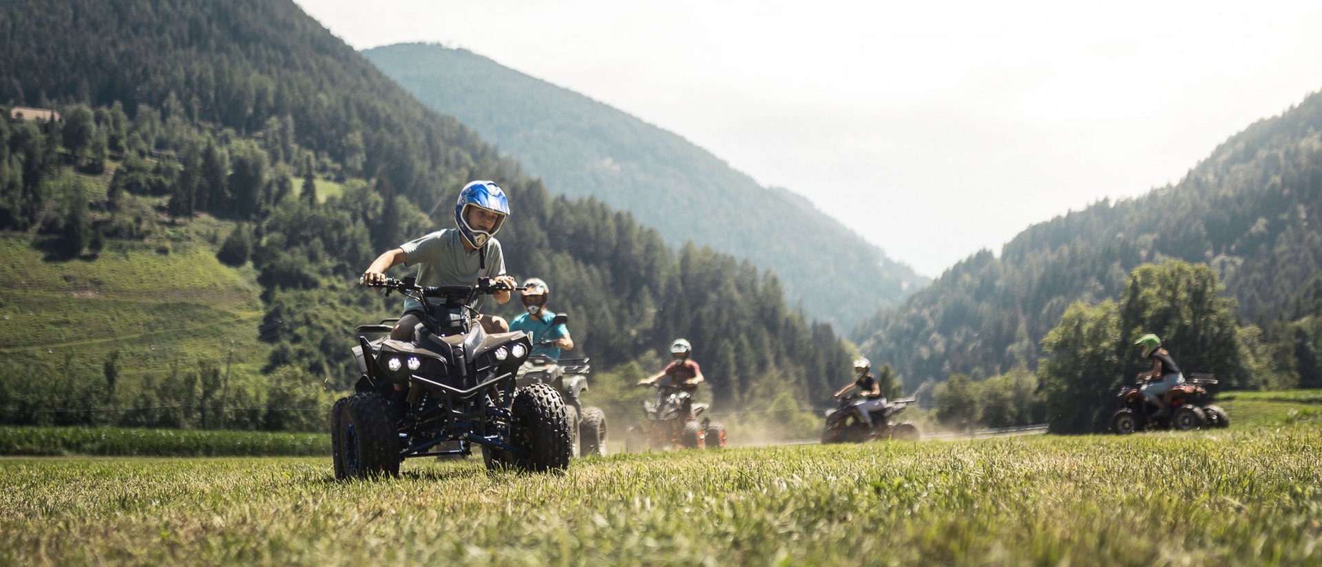 Kinder fahren Quad in bergiger Landschaft bei sonnigem Wetter