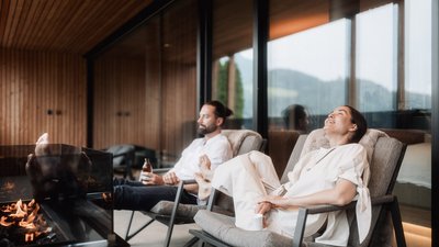 L’esclusività in foto: il nostro chalet in Alto Adige di lusso Coppia rilassata su sedie vicino a un caminetto in casa moderna