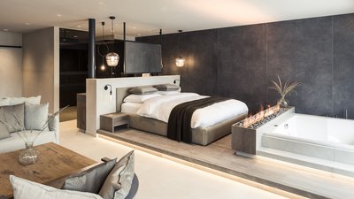 L’esclusività in foto: il nostro chalet in Alto Adige di lusso Suite d'hotel moderna con letto, camino, vasca idromassaggio e area salotto