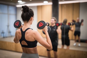 Persone che sollevano pesi davanti a uno specchio in palestra