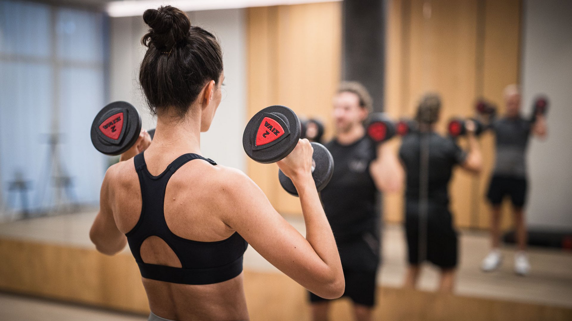 People lifting weights in front of a mirror in a gym