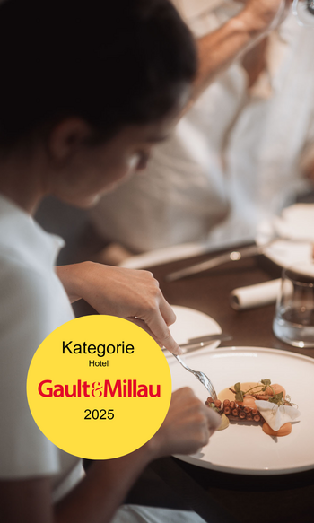 Die Heimat des Strahlens: Ihr Wellnesshotel in Südtirol Person isst ein kunstvoll angerichtetes Gericht in einem Gault&Millau Hotel 2025