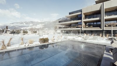 Photos from your hotel in Pfalzen in Val Pusteria/Pustertal Heated outdoor pool with snow and modern building in the background